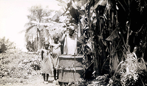 The woman, Imama, is stirring a dyeing vat with two girls looking on.