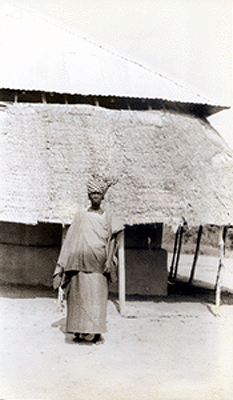 Woman standing in front of a thatched house